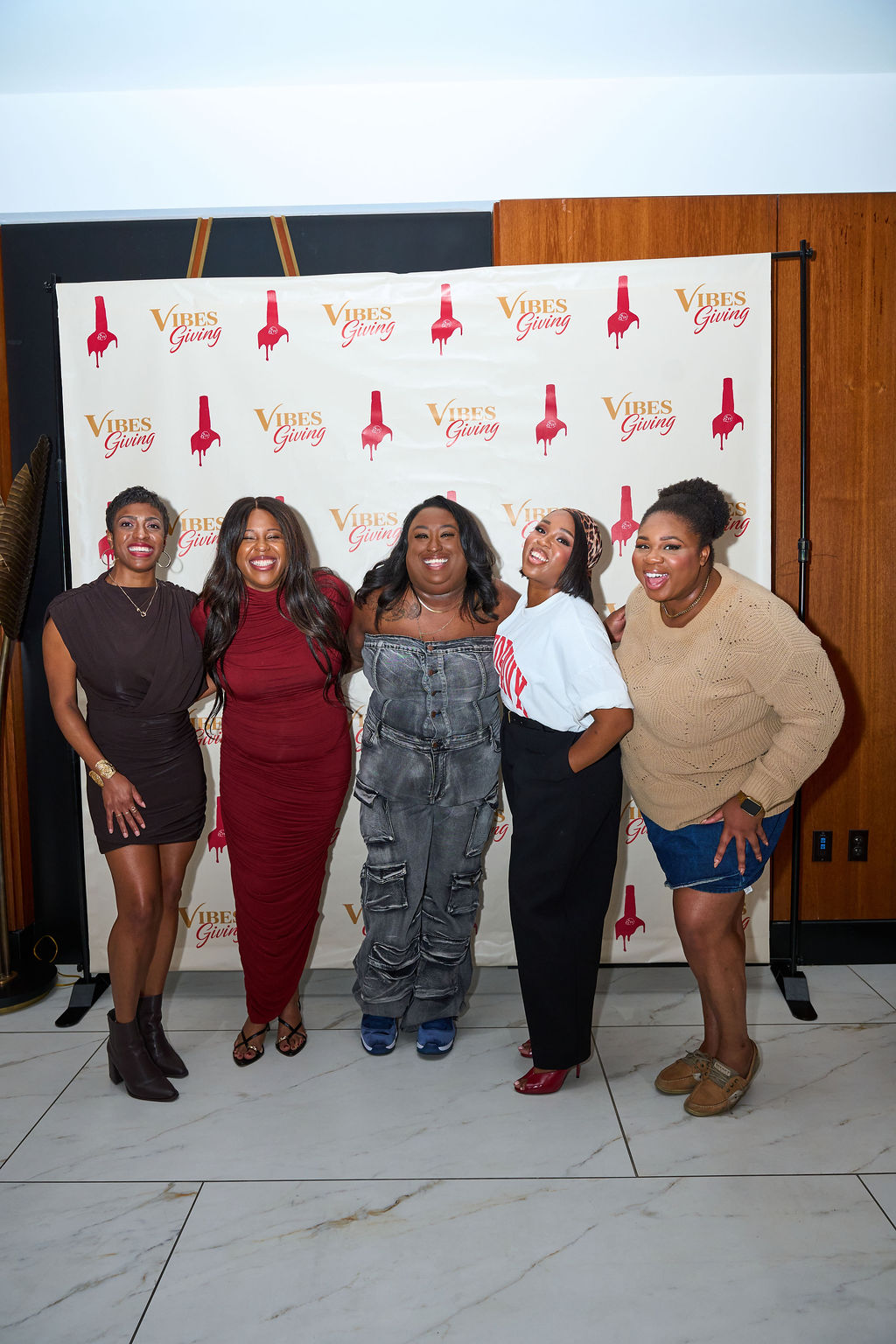 Group of friends posing in front of the Vibesgiving branded backdrop